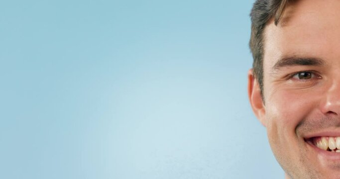 Half face, smile and mockup with a man on a blue background in studio for marketing or advertising. Portrait, space and a happy young person closeup on an empty background for branding or a logo