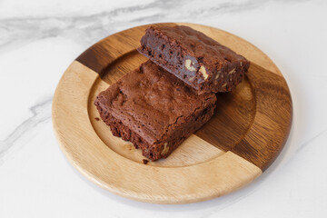 Brownie aux noisettes sur une assiette en bois et table en marbre. Gâteau au chocolat.
