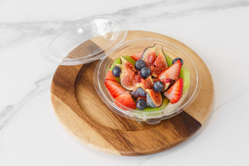 Salade de fruits composée de fraises, figues, myrtilles et kiwi à emporter.