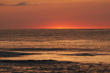 The glowing sun sinking on the horizon of the sea or ocean