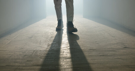 Legs of Maniac escaping from crime scene. Bloodthirsty criminal in hallway of old house. backlighting of a mans legs in the dark of a foggy night and a light behind the model