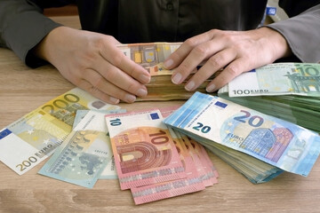hand counting the big stack of euro money on wooden background. money cash