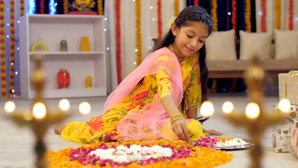 A cute little girl wearing a suit and decorating flower rangoli with flower petals  Indian tradition in festivals. Indian stock footage of a cute girl decorating her house for festive preparations ...