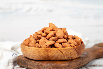 Almond in wood bowl. Roasted almonds on white wood background