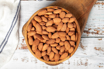 Almond in wood bowl. Roasted almonds on white wood background. Top view