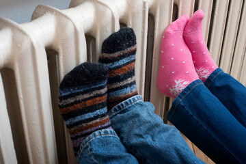 Couple warming up their feet on central heating radiator