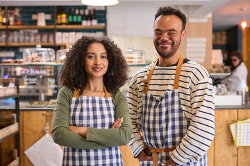 Portrait Of Woman Wearing Apron And Man With Down Syndrome Working In Food Shop Together