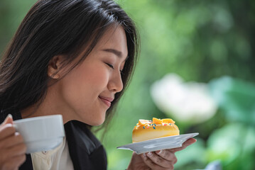 Asian girl holding look surprise dessert cake in hand and smell taste sweet cream. Smiling woman eating fancy piece of chocolate fruit cake in birthday celebration party. - obrazy, fototapety, plakaty