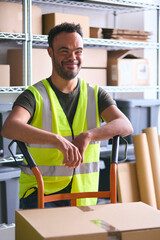 Portrait Of Man With Down Syndrome Working In Warehouse Wearing Hi Vis Safety Vest