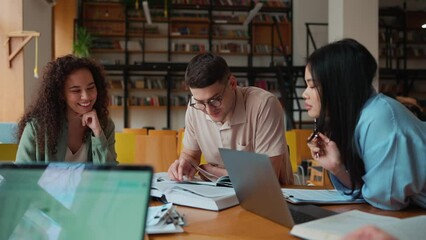 Group of positive multicultural students studying and talking in the library - Powered by Adobe