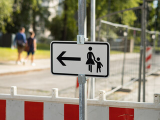 German traffic sign for pedestrians to change the side of the street because of a construction site. Detour for people on the sidewalk.