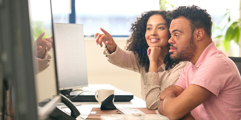 Woman Working In Office Based Business Training Man With Down Syndrome Using Computer