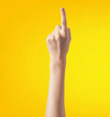 Fototapeta premium Female hand showing the middle finger on a yellow background with copy space