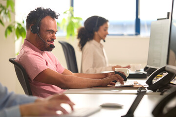 Man With Down Syndrome Wearing Headset Working In Office Call Centre Team