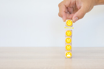 Emoticons smile face on cube wooden block stack for customer services rating feedback satisfaction survey business review and exchanges development for service mind and marketing plan management.