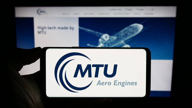 Stuttgart, Germany - 09-10-2023: Person holding cellphone with logo of German aviation company MTU Aero Engines AG on screen in front of business webpage. Focus on phone display.