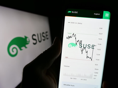 Stuttgart, Germany - 09-10-2023: Person holding cellphone with website of open-source software company SUSE S.A. on screen in front of logo. Focus on center of phone display.