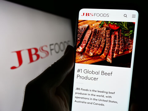 Stuttgart, Germany - 09-10-2023: Smartphone with webpage of meat processing company JBS USA Holdings Inc. on screen in front of business logo. Focus on center of phone display.