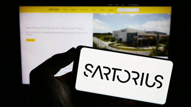 Stuttgart, Germany - 09-10-2023: Person holding cellphone with logo of German pharmaceutical company Sartorius AG on screen in front of business webpage. Focus on phone display.