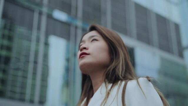 Low angle view of young asian businesswoman walking in the street with confidence and ambition mood slow motion