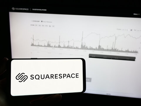Stuttgart, Germany - 09-11-2023: Person holding mobile phone with logo of US website building company Squarespace Inc. on screen in front of web page. Focus on phone display.