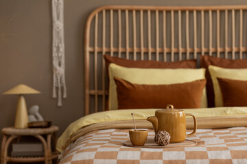 Warm and cozy living room interior with wooden bed, chess board print bedding, yellow pitcher, cup,...