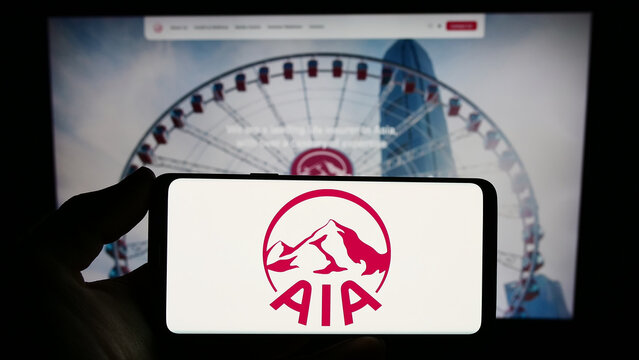 Stuttgart, Germany - 09-13-2023: Person holding smartphone with logo of insurance company AIA Group Limited on screen in front of website. Focus on phone display.