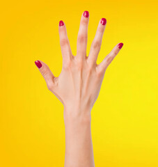 The image shows a close-up of a female hand with red nail polish, isolated against a yellow background.