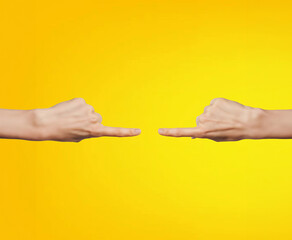 Two hands pointing at each other on a yellow background with copy space