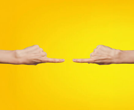 Two hands pointing at each other on a yellow background with copy space