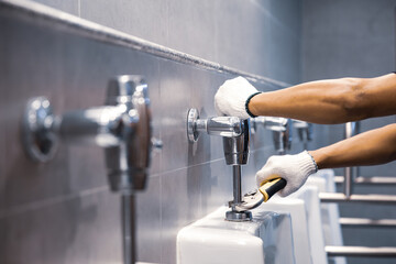 Hand of handyman or plumber is using a wrench to fix or repair leaking water pipes, faucets or...