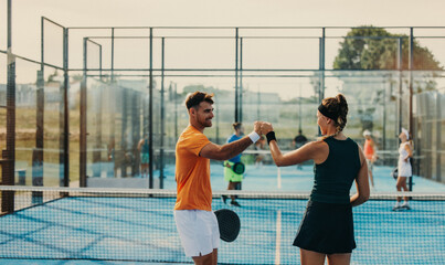 Padel athletes celebrating with fist bumps in a doubles match