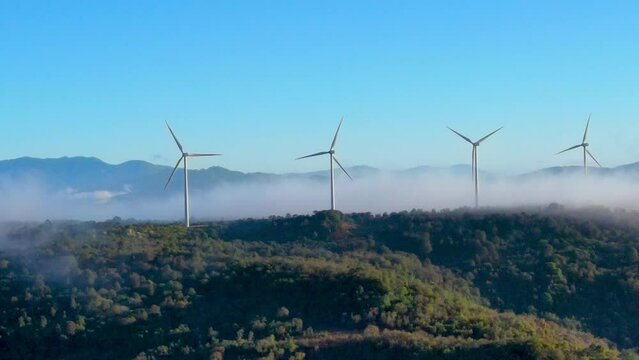 Lateral aerial panning on some wind turbines that are with some morning fog