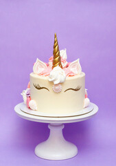 Unicorn cake with white frosting and copy space to side, purple background