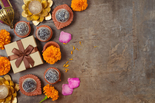 Diwali holiday concept with sweet traditional dessert, gift box and decorations on dark background. Top view, flat lay