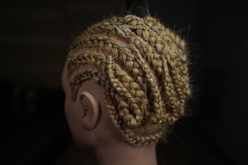 African braid with Kanekalon on a mannequin, afro-locks on a frame, frame hairstyles, afro-curls, a base for hair extensions, a thin braid is braided over the head of a mannequin