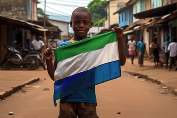 Un garçon sierra leonais tenant le drapeau du Sierra Leone, dans une rue de Freetown