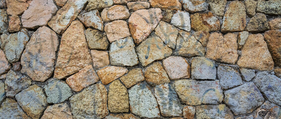 Fragment of a natural stone wall as a background or texture. The structure of the stone wall. Old castle stone wall texture background.