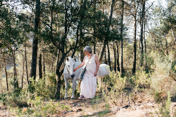 Happy middle aged woman standing and bonding with horses in countryside