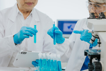 Two Asian scientists in the laboratory or medical personnel looking at a microscope in the lab