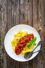 Tagliatelle con ragù alla bolognese - pasta with minced meat and tomato sauce on wooden table
