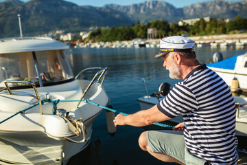 Mature man standing near the sea dressed in a sailor's shirt and hat.