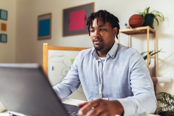 Handsome African American smiling freelancer working remotely from home