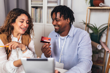 Portrait of young business people ordering something online with card in home office. Couple teamwork startup concept