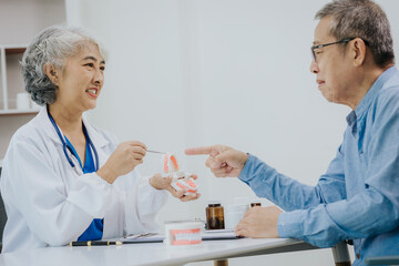 Dentist consults oral hygiene of patient's teeth at table with molar samples in professional dental clinic.