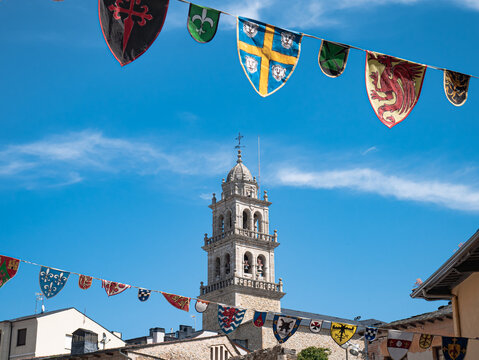 Medieval flags and pennants decorate the streets of Ponferrada during the Encina festivities in Ponferrada on a sunny day and the tower of the Basilica of Nuestra Se&ntilde;ora de la Encina in the background