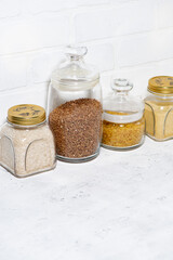 assortment of cereals in glass jars on a white background, vertical top view