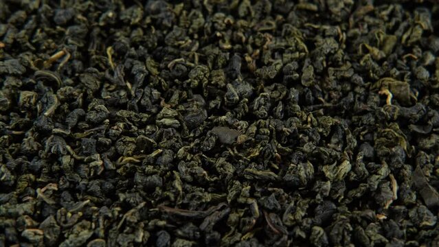 Black Dry Tea Wallpaper. Wooden spoon picks up Mix Black and Green Tea Leaves. Close Up, Macro. Top View. Texture. Copy Space. Dried Tea is Spinning, Rotating on Turntable. Food and Drink Background	
