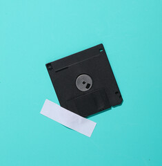 Floppy disk is taped to a blue wall. Conceptual photo, minimalism.