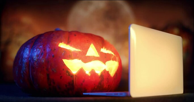 Halloween Pumpkin Jack-o-Lantern using laptop. Holiday october, laptop online Halloween concept. Pumpkin watching content online